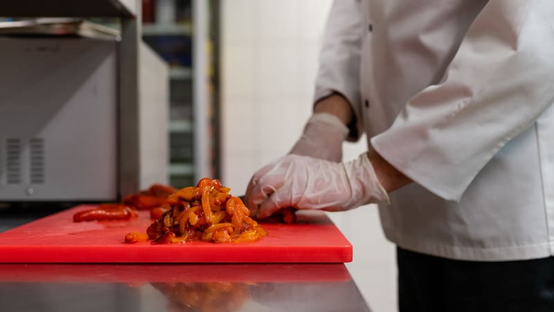 Chef en cuisine professionnelle avec planche de découpe aux normes HACCP
